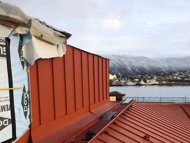 Pågående arbeid på tak med utsikt over Tromsø