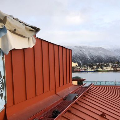 Pågående arbeid på tak med utsikt over Tromsø